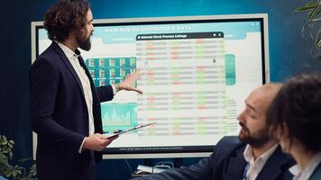 Startup team deliberates on strategic plans and financial projections during executive meeting, manager gives clipboards with infographics. Deciding resource allocation with data reports. Camera A. photo