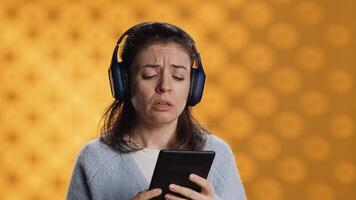 Voice actor frowns while reading ebook, portraying character, studio background. Woman reenacting digital recording of novel, interpreting furious antagonist, reading text from tablet, camera A photo