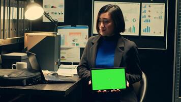 Private detective using tablet showing greenscreen template in incident room, working with witness statements and classified records. Agent holding device with isolated mockup. Camera A. photo