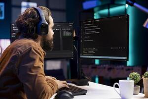 IT programmer listening music while fixing vulnerabilities in software enabling hackers to compromise operating system. Cybersecurity expert wearing headphones and using PC to patch security exposures photo