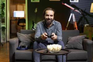 Portrait of smiling man playing shooter videogame in neon lit room, holding controller. Cheerful person participating in esports competition using professional gamepad for better victory chances photo