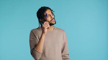 Middle Eastern man thinking, tapping pen to forehead, coming up with idea concept. Pensive person contemplating, doing introspection, having eureka moment, studio background, camera A photo