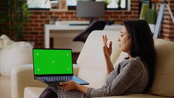 Manager at home delegating tasks to team while in videoconference meeting on green screen laptop. Indian woman using chroma key notebook for videocall, offering project guidance to employees photo
