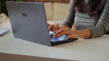 Teleworker writing emails on laptop, sending them to business partners. Employee working from home in bright stylish cozy apartment personal office, typing on notebook keyboard, camera A close up photo