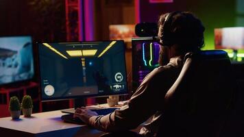 Man coming to gaming station, excited to finally relax by playing SF videogame on PC at computer desk late at night. Gamer starting game, battling foes in online multiplayer futuristic shooter photo
