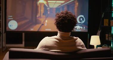 BIPOC man playing shooter videogame on ultrawide smart TV in futuristic industrial setting with health, stamina, ammo bars HUD overlay. Zoom in shot of gamer enjoying PvP fps online multiplayer game photo