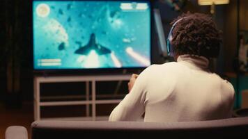 Gamer putting on headphones to feel immersed in intense classic arcade space shooter videogame. Man relaxing in apartment using high tech gaming system to play singleplayer game photo