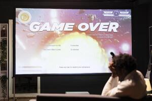 Upset man losing science fiction singleplayer game on gaming console, feeling sad. Player failing to win videogame, annoyed after being defeated by enemies and getting spaceship destroyed photo