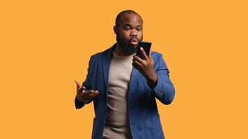 Irked african american man fighting with friends during telephone call, isolated over studio background. Outraged person arguing with mates during conversation on mobile phone, camera B photo