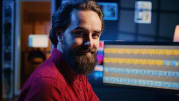Portrait of smiling photographer using photo editing software on PC display in multimedia creative studio. Happy freelancer using photographs retouching program, zoom in shot