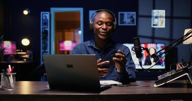 Portrait of BIPOC tech vlogger reviewing newly released smartphone in rgb lights living room studio. Entertaining influencer filming technology channel episode using professional tools photo