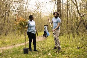 Team of diverse activists doing voluntary work to plant trees in the woods, protecting natural forest environment. Planting seedings for future generations, giving life and helping the planet. photo