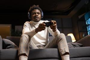 Man focused on defeating enemies while playing videogames on gaming console with teammates, talking through headphones. Gamer fights rival players using gamepad, chatting with friends through headset photo