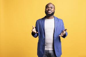 Portrait of smiling african american man posing with hands spread, exuding self assurance, isolated over studio background. Expressive BIPOC person moving arms while talking photo