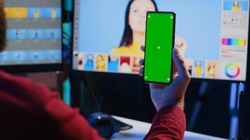 Photographer watching tutorial on mockup mobile phone to learn how to professionally enhance images quality. Photo editor following guide on green screen smartphone about using retouching software