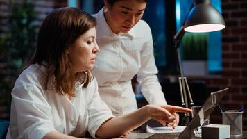 Worker calling manager at workstation to look over paperwork and give feedback on company project. Businesswoman brainstorming with team leader, looking over accounting figures on laptop photo