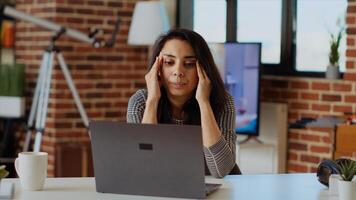 Self employed woman feeling ill, struggling to concentrate while working from home, hurting from headache. Exhausted freelancer suffering from sickness and stress while working on laptop, camera B photo