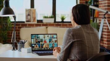 Teleworking management executive in apartment discussing with coworkers during videoconference meeting. Manager holding online videocall with remotely working employees, camera B photo