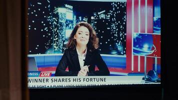 Cheerful woman in newscasting studio talking about various stories on news channel. Ultrawide modern TV set in empty living room showing reporter presenting news coverage photo