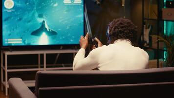 Player in home theatre enjoys game with spaceship shooting laser streams using crosshair overlay to hit enemies. Ray tracing graphics and high FPS SF videogame displayed using projector photo