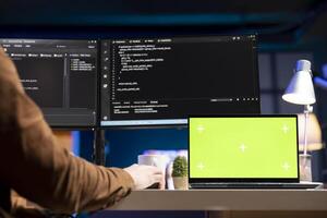Admin using green screen laptop to filter malicious traffic from cybercriminals attempting to corrupt company data. IT expert working on chroma key notebook, preventing malware and phishing attacks photo