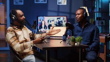 Podcast presenter having live discussion with man, using headphones to review music together. Influencer enjoying chat with guest, streaming it for audience on internet show photo
