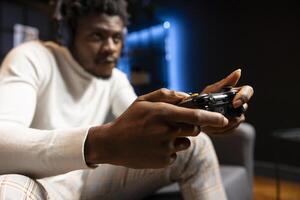 Man playing videogames using controller, having fun in blue neon illuminated room. Gamer competing in online multiplayer game on gaming console using gamepad, talk with friends through headset photo