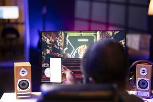 Man watching favorite content creator on isolated screen smartphone showing tips for game he is currently playing, close up. Player looking online for inspiration on mockup phone, stuck on mission photo