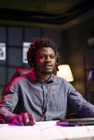 Gamer sitting in front of computer desktop, playing competitive videogames while streaming for audience. Media star enjoying gaming session on powerful rgb lit PC, broadcasting online for viewers photo