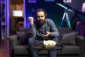 Gamer wearing headphones frustrated after getting game over message while playing videogame. Man in home theatre spending time on gaming console, angry after losing level photo