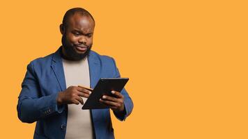 Man frowning while adding payment method on website, seeing insufficient funds error, studio background. Upset person getting transaction rejected, wrongly typing credit card data on tablet, camera A photo