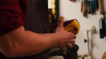 Carpenter putting sandpaper on piece of plastic, creating abrasive sponge to smooth surfaces. Man preparing necessary gear for furniture assembling job in studio, close up shot, camera A photo