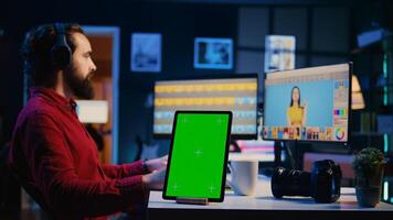 Green screen tablet on desk in graphic design company next to content specialist selecting best editorial pictures for social media. Mockup device near expert editing photos in advertising agency