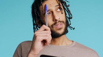 Portrait of man deliberating, putting pen on lips, coming up with idea concept. Thoughtful person reflecting, doing brainstorming, having eureka moment, studio background, camera B close up photo