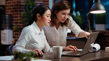 Asian employee brainstorming with coworker to compose email at computer desk, finalizing deal with business partners. Businesswoman and colleague closing agreement with associates, camera B photo