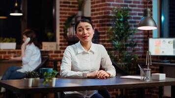 POV of smiling asian worker greeting colleagues during business meeting on videocall in office. Portrait of friendly employee participating in remote videoconference telework call photo