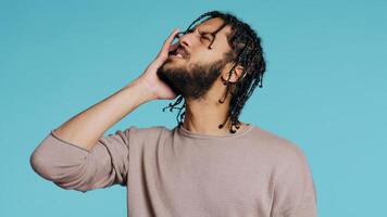 Hurt Middle Eastern man wincing from pain, suffering from headache, having health problems. Injured BIPOC person rubbing head temples, feeling discomforting strain, studio background, camera B photo