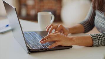 Teleworker writing emails on laptop, sending them to business partners. Employee working from home in bright stylish cozy apartment personal office, typing on notebook keyboard, camera B close up photo