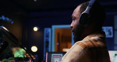 Close up of BIPOC man talking with woman, streaming podcast using vlogging camera during live political debate on vlog channel. Host in dimly lit studio filming internet show, panning shot photo