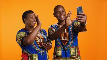 Ethnic couple waving hello on online videocall connection, using internet network and link to chat with family members. Husband and wife holding smartphone to talk to people on web. photo