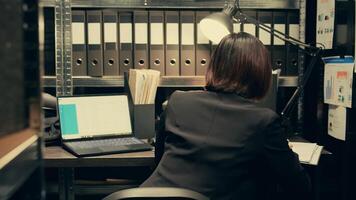 Private investigator comparing sources to confirm case details or cross check confidential information, compiling statistical data on crime trends. Asian federal agent in incident room. Camera B. photo