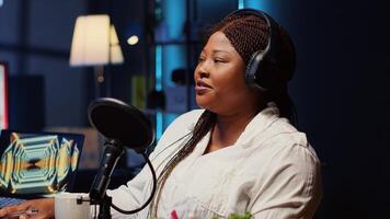 Guest on online podcast show telling interesting story to host, captivating viewers watching during live broadcast. African american woman in studio sharing facts, surrounded by audio tech photo