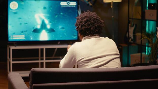 Gamer playing classic arcade space shooter videogame on big smart TV, shooting asteroids using laser beams. Man relaxing at home using high tech gaming console to solve missions in singleplayer game photo