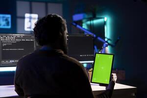 Cybersecurity expert using isolated screen tablet to look for security vulnerabilities and injected malware. Programmer installing fortified code on mockup portable device to prevent cyber attacks photo
