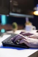 Computer engineer in apartment designing and developing software applications, close up shot. IT professional typing on keyboard, implementing and maintaining company systems photo