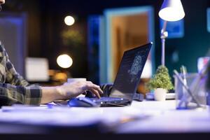 Person typing and computing code on laptop to build databases. Closeup of a male individual working from home, checking the data center and software system, creating ai futuristic neural networks. photo