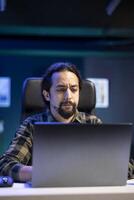 Male freelancer analyzing network information on laptop, planning statistics for business presentation. Dedicated project researcher working at home, on online website application. photo