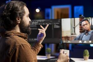 Engineer doing software debugging helped by BIPOC coworker in videocall meeting, checking errors in lines of code. IT worker fixing coding mistakes assisted by colleague in online teleconference photo