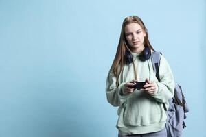 Young gamer girl holding controller, focused on finishing difficult videogame level. Woman gaming with gamepad and solving quests, being entertained, isolated over studio backdrop photo