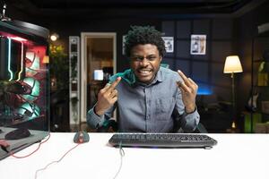 latón jugador a computadora escritorio insultante rival jugadores mientras jugando competitivo multijugador Juegos de vídeo. fresco hombre lanzamiento medio dedos gesticulando a oponentes en Internet esports juego foto